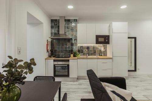 a kitchen with white cabinets and a table with chairs at Amadora Flat 3 in Amadora
