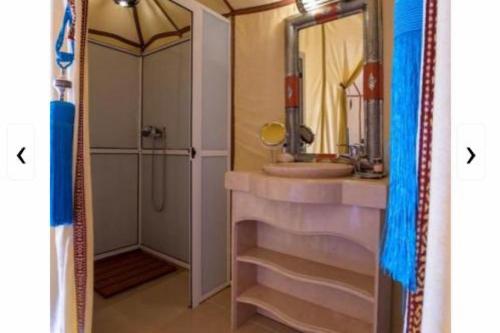 a bathroom with a sink and a shower with a mirror at Merzouga Exclusive Camp in Merzouga
