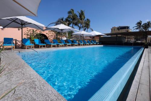 a swimming pool with blue chairs and umbrellas at La Posada Hotel Boutique in Manzanillo