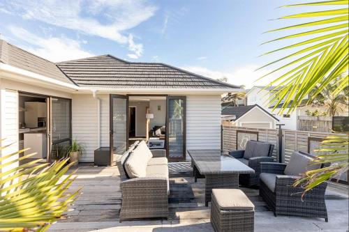 a patio with couches and a table on a house at Your Downtown Mount Maunganui Escape Awaits! in Mount Maunganui