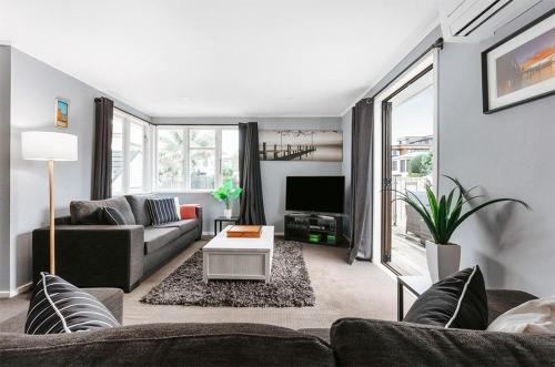 a living room with a couch and a tv at Your Downtown Mount Maunganui Escape Awaits! in Mount Maunganui