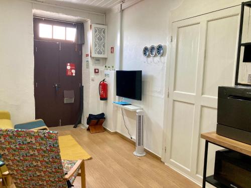 a living room with a tv and a door and a room with a chair at Casinha do Solar in Angra do Heroísmo