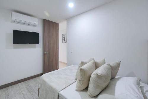 a white bedroom with a bed with pillows on it at Luxury air conditioning near laureles in Medellín