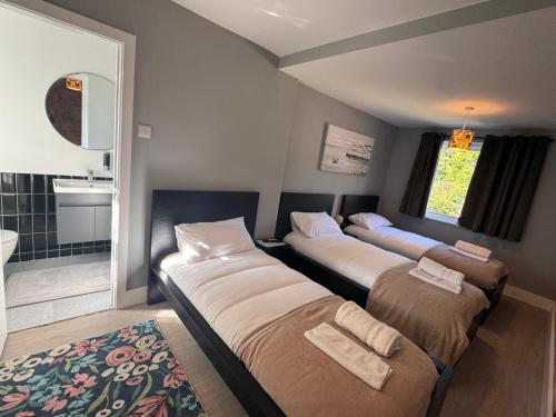 three beds in a room with a bathroom at 40th Avenue Guest House in Mill Hill