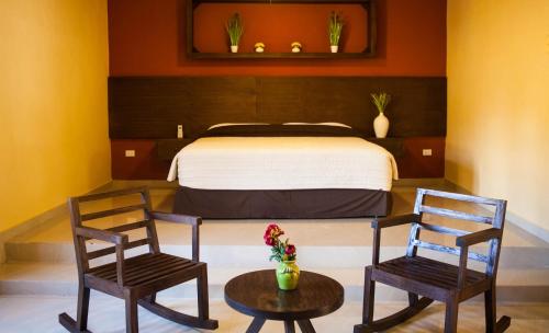 a bedroom with a bed and two chairs and a table at Villa San Antonio de Padua in Izamal