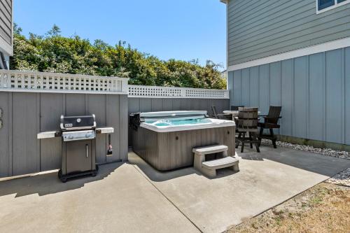 a backyard with a hot tub and a grill at Stella Blue in Corolla