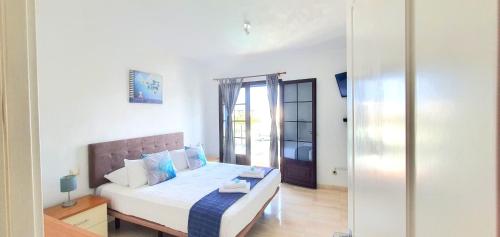 een slaapkamer met een bed met witte lakens en blauwe kussens bij Casa Yaiza in Playa Blanca