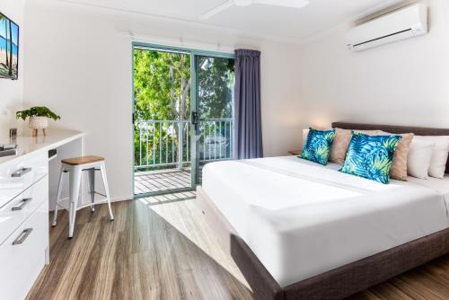 een witte slaapkamer met een bed en een balkon bij Sunset Water Premium 2 bedroom in Hamilton Island