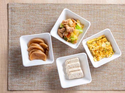 four white dishes of food on a table at Super Hotel Hida Takayama in Takayama