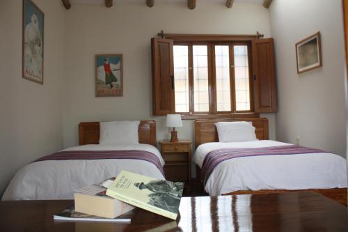 a room with two beds and a book on a table at Maison Fortaleza in Cusco