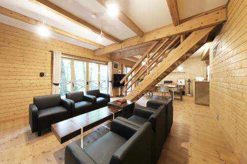 a living room with black leather furniture and wooden walls at 旧軽井沢 AZ-BASE Karuizawa in Karuizawa