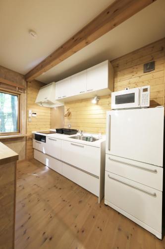 a kitchen with a white refrigerator and a microwave at 旧軽井沢 AZ-BASE Karuizawa in Karuizawa