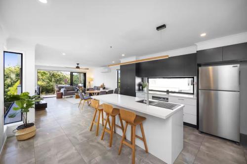 a kitchen with a white counter and stools in it at Absolute Beachfront Marcoola 4BR, Heated Spa in Marcoola