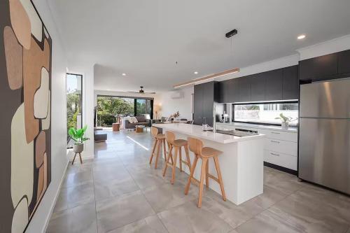 a kitchen with a white counter and stools in it at Absolute Beachfront Marcoola 4BR, Heated Spa in Marcoola
