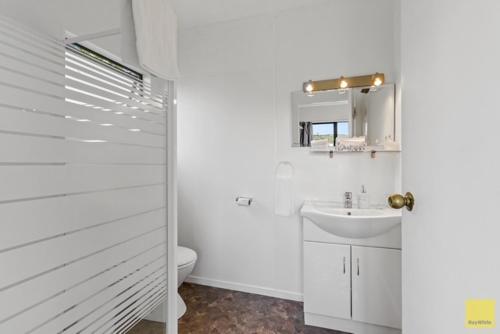 a white bathroom with a sink and a toilet at Waitomo Caves Guest Lodge in Waitomo Caves