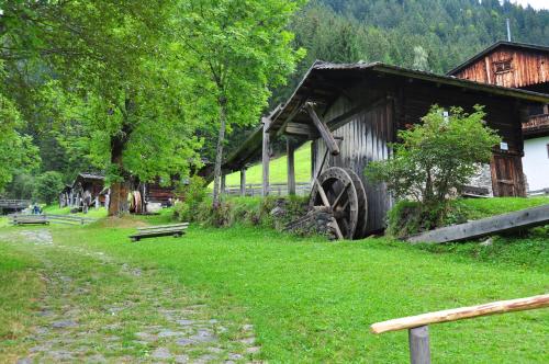 a barn with a large wheel next to a field at Familienwanderhof Eggeler in Liesing