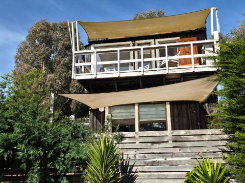 ein Haus mit einem Balkon oben auf der Treppe in der Unterkunft Cabañas VistaMar en Lomas de Farr Pelluhue in Pelluhue