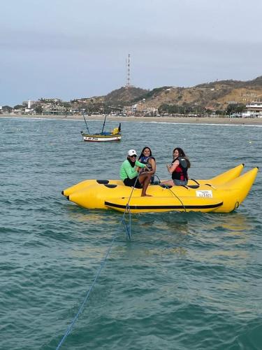 three people sitting on a yellow boat in the water at Mango & Apartments in Tumbes