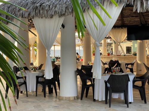 a restaurant with white tables and chairs and palm trees at Mango & Apartments in Tumbes