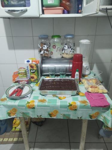 a table in a kitchen with a table with a tray of food at Quarto em casa de Família- Riacho in Brasilia
