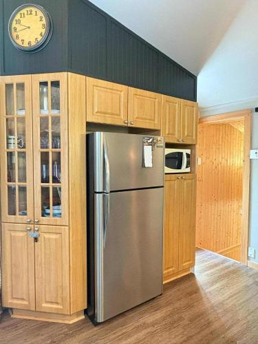 a kitchen with a refrigerator and a clock on the wall at Le Rassembleur in Saint Adolphe D'Howard