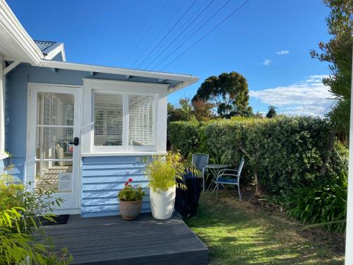 a blue house with a porch with a table and chairs at Saltwater Studio in Motueka