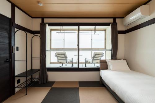 a bedroom with a bed and a window with chairs at J style villa Sapporo フルリフォーム 長期滞在にもオススメ マーケット近く in Sapporo