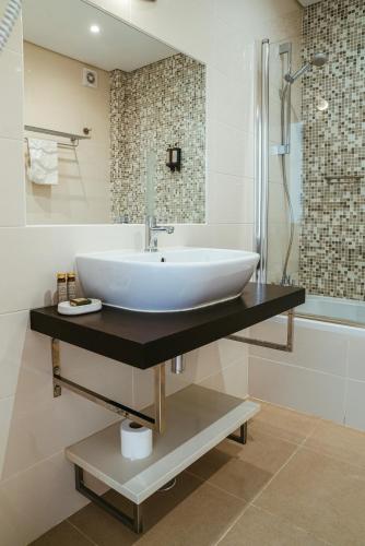 um banheiro com pia, chuveiro e banheira em Moradias Villas Rufino em Albufeira