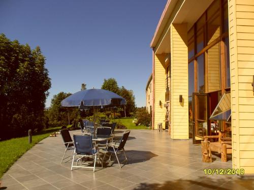 a patio with chairs and an umbrella next to a building at Hotel Patagonia Insular in Quellón
