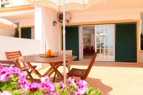 a wooden table and chairs on a patio with pink flowers at Moradias Villas Rufino in Albufeira