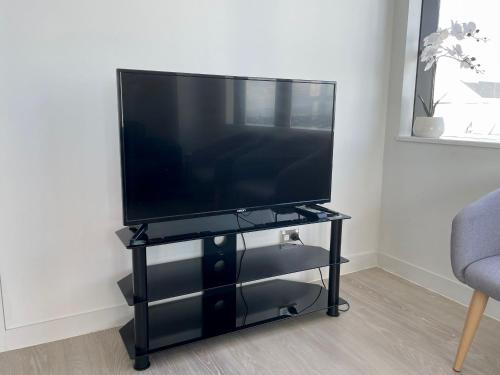 a flat screen tv on a black stand in a living room at Just opposite to Skytower, 2 Bed 2 Bath in CBD in Auckland
