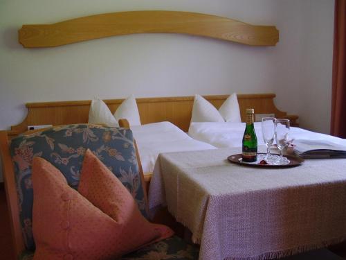 a hotel room with two beds and a table with a bottle of champagne at Gästehaus Elfriede in Gerlos