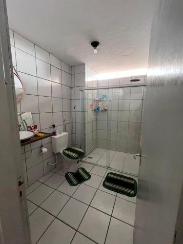 a white tiled bathroom with a shower and a sink at Hospedagem da Mag in João Pessoa