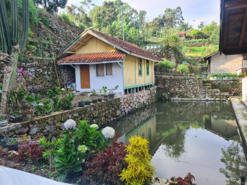 a house with a pond in front of it at Zann Villa Ciwidey in Panundaan