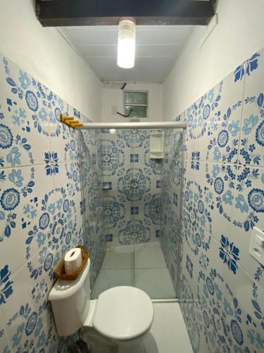 a bathroom with a toilet and blue and white tiles at Chalé Tiririca Surf & Mar in Itacaré