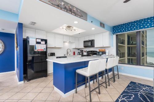 a kitchen with white cabinets and blue walls at Phoenix I 1078 condo in Orange Beach