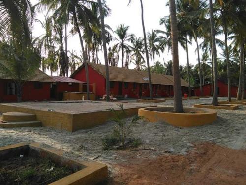 un bâtiment rouge avec des palmiers devant lui dans l'établissement Manan Guest House, à Malpe