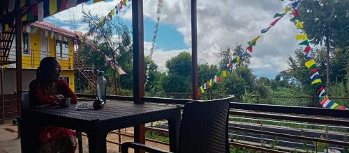 a woman sitting at a table looking out a window at a train at Everest Home Stay Temal Kalimati Tower in Thapathali