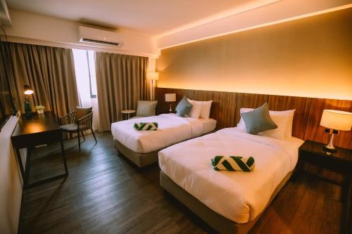 a hotel room with two beds and a desk at The Maximilian Hotel in Cauayan City