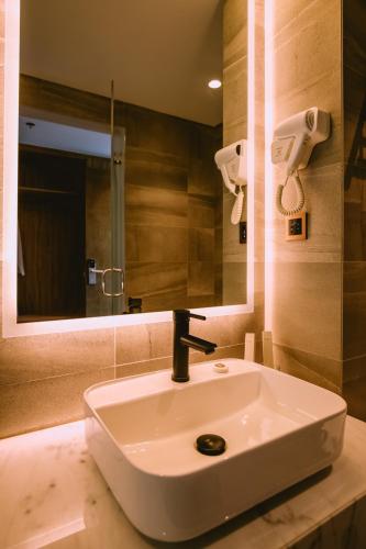 a bathroom with a white sink and a mirror at The Maximilian Hotel in Cauayan City