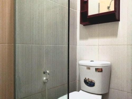 Un baño con inodoro y ducha de cristal. en Fatih Homestay, en Bandung