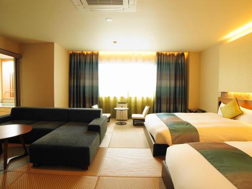 a hotel room with two beds and a couch at ジュラシック スパ &リゾート くつろぎの宿 樹楽 in Toon