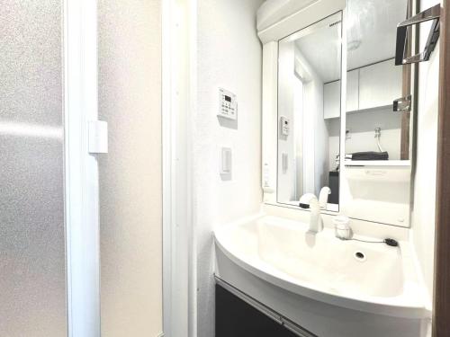 a white bathroom with a sink and a mirror at ToyoHomes西新宿 in Tokyo