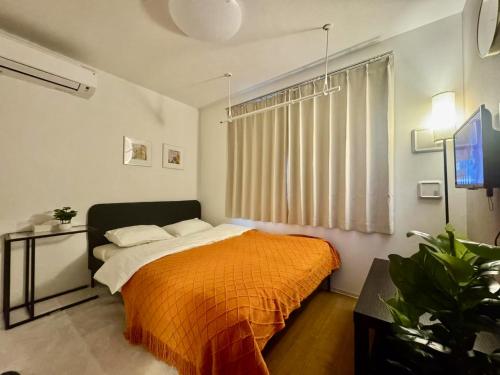 a bedroom with a bed with an orange blanket at ToyoHomes西新宿 in Tokyo
