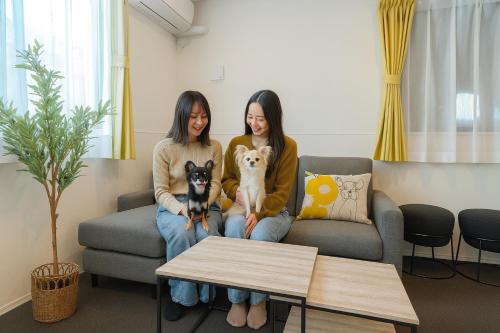 two women sitting on a couch with two dogs at Casa Stella 8 by Liaison カーサステラ8 byリエゾン in Osaka