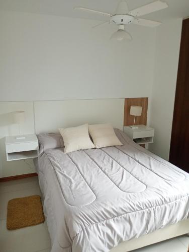 Un dormitorio blanco con una cama y dos mesitas de noche. en Sueños, en Villa Carlos Paz
