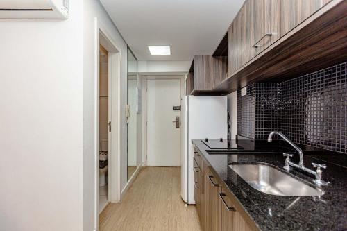 una cocina con fregadero y refrigerador en Studio Moderno no Centro com Piscina, Vista Panorâmica e Garagem, en Curitiba
