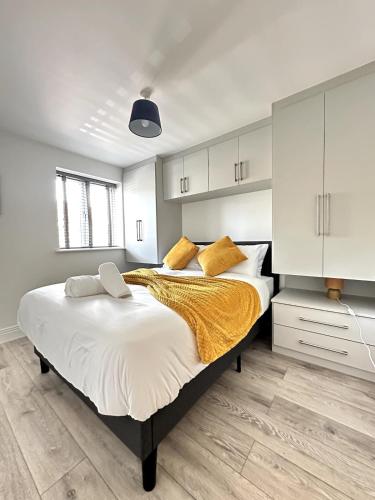ein Schlafzimmer mit einem großen Bett mit gelben Kissen in der Unterkunft Modern Ground floor 2 Bed Room Apartment Work Leisure Free Parking in Woking