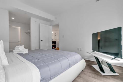a white bedroom with a bed and a flat screen tv at Fully Furnished Apartment in Washington near Logan Circle in Washington