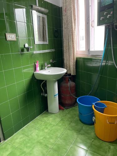 a green tiled bathroom with a sink and a bucket at Pema Guest House in Kathmandu